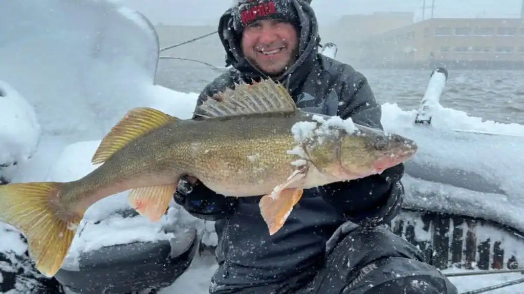 Wisconsin angler holding walleye with snow-covered boat — Find Boat Services